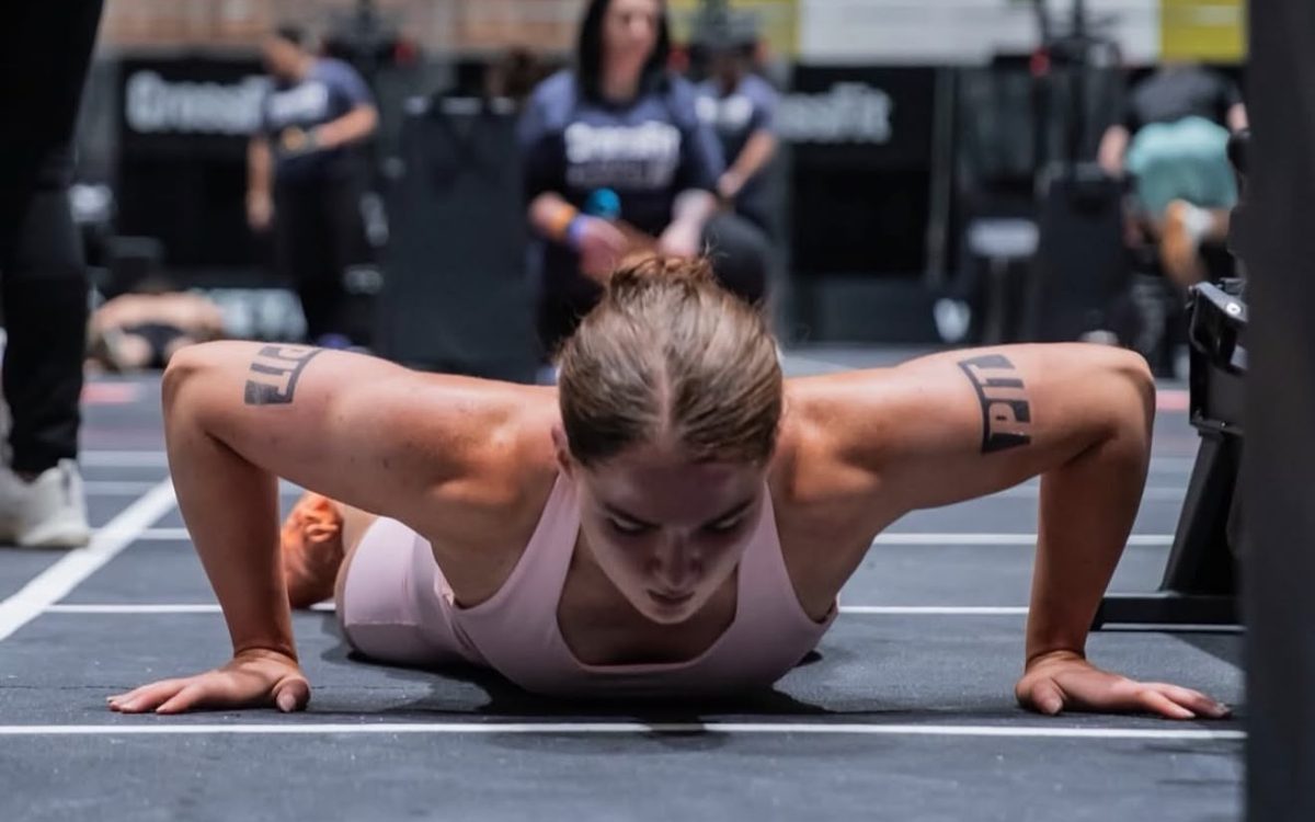 An athlete at the bottom of a press-up on a competition floor