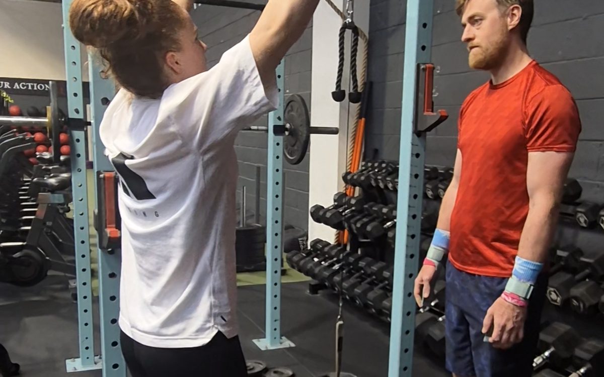 Charlotte setting up a barbell in a squat rack while a client watches