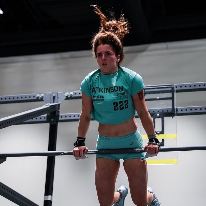 An athlete hanging at the top of a pull-up bar