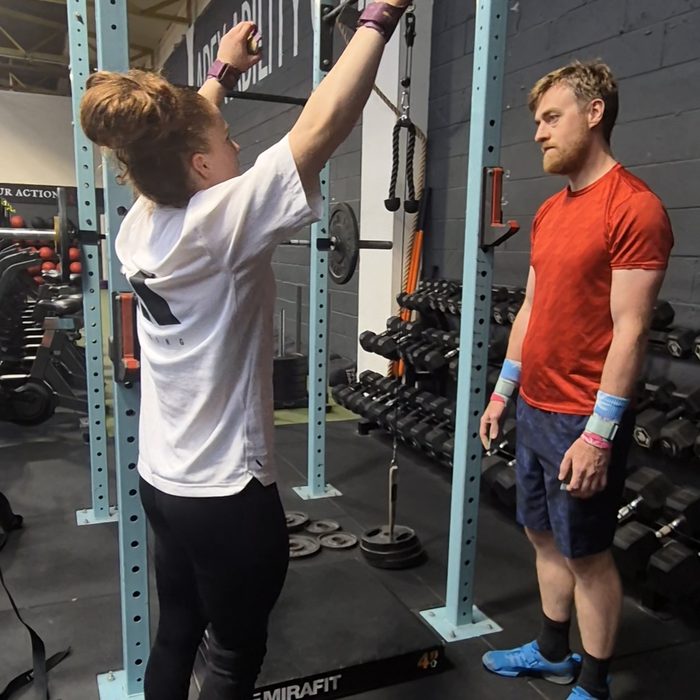 Charlotte coaching a client at a squat rack